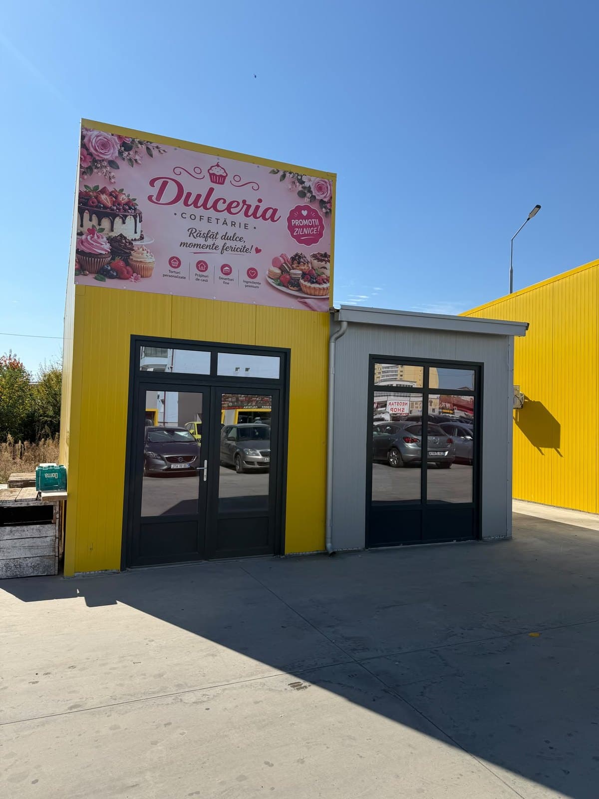 Chioșcul galben Dulceria Cofetărie, cu firma roz deasupra intrării